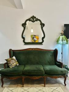 un sofá verde en la sala de estar con espejo en Parrot Chic Apartment, en Bar