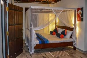 a bedroom with a canopy bed with pillows at Heaven View Tangalle in Tangalle
