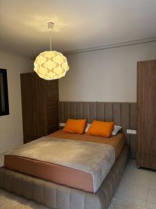 une chambre avec un lit avec des oreillers orange et un lustre dans l'établissement Élégante villa familiale à Harhoura Confort et Proximité plage, à Temara