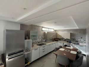 Il dispose d'une grande cuisine avec une table et un réfrigérateur. dans l'établissement Élégante villa familiale à Harhoura Confort et Proximité plage, à Temara 12 autres photos