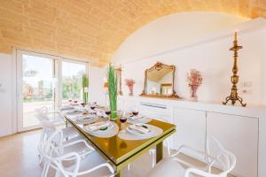 een eetkamer met een tafel en witte stoelen bij KYVOS 10, Emma Villas in Marina di Leuca