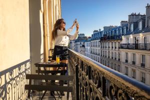 eine Frau, die auf dem Sims eines Gebäudes steht in der Unterkunft Grand Hôtel Lévêque in Paris