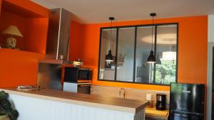 eine Küche mit orangefarbenen Wänden und einem großen Spiegel in der Unterkunft Aux rives du lac in Villefranche-de-Panat