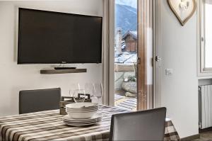a dining room with a table with a tv on the wall at Genziana 2 - AffittiPontediLegno in Ponte di Legno