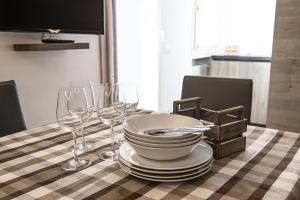 a table with plates and wine glasses on a checkered table cloth at Genziana 2 - AffittiPontediLegno in Ponte di Legno