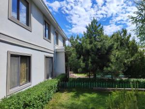 a white building with a yard next to a tree at Laguna rest mini in Grigor'yevskaya Pristan'