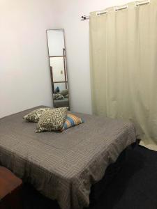 a bedroom with a bed with a mirror on the wall at Quartos a 50 metros da praia in Itapema