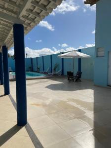eine Terrasse mit Sonnenschirm und Swimmingpool in der Unterkunft Casa de praia No Abais in Praia Da Caueira