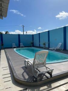 einen Stuhl auf einer Terrasse neben einem Pool in der Unterkunft Casa de praia No Abais in Praia Da Caueira