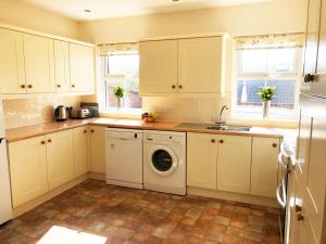 a kitchen with white cabinets and a washing machine at White Lion Aberporth in Aberporth
