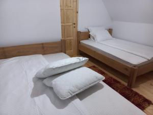 two beds in a room with white sheets and pillows at Căsuța bunicii in Cavnic