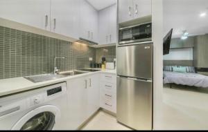 eine Küche mit einem Edelstahlkühlschrank und einer Waschmaschine in der Unterkunft 308 Lovely Cosy Entire Private Studio Apt Central in Melbourne