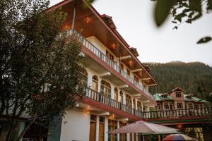 KalghaLIGHTWORKERS Hostel & Cafe的带阳台和遮阳伞的大型建筑