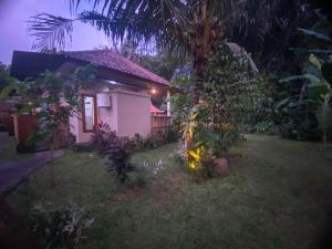 una pequeña casa blanca con una palmera en el patio en Semana Jungle by SHM, en Ubud