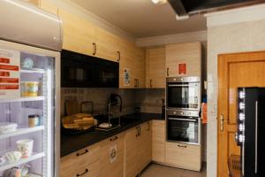 a kitchen with wooden cabinets and a refrigerator at Lisbon Surf Hostel in Carcavelos