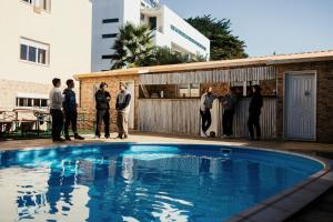 a group of people standing around a swimming pool at Lisbon Surf Hostel in Carcavelos