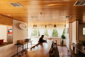a man sitting at a large wooden table in a room at Lisbon Surf Hostel in Carcavelos