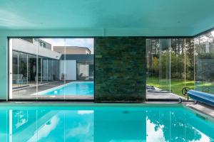 a swimming pool in a house with glass walls at Lux Villa with heated indoor Pool at Aroeira Sea & Golf Resort - Lisbon in Almada