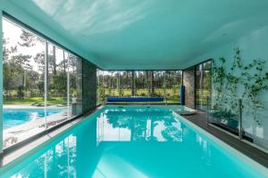 an indoor swimming pool with glass walls and a large window at Lux Villa with heated indoor Pool at Aroeira Sea & Golf Resort - Lisbon in Almada