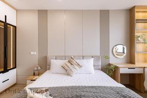 een slaapkamer met een bed met witte lakens en een spiegel bij OriGem - Skyview Căn Hộ 2 PN in Thu Dau Mot +50 foto's