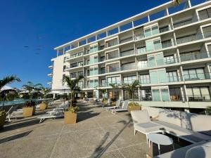 a large building with white chairs and tables in front of it at Zantamar Beach Front La Cruz in Cruz de Huanacaxtle