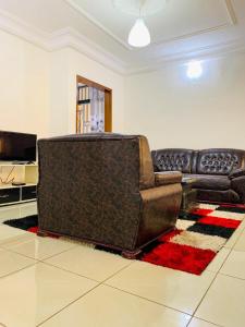 a living room with a leather couch and a television at Résidence Soleil Levant in Yaoundé