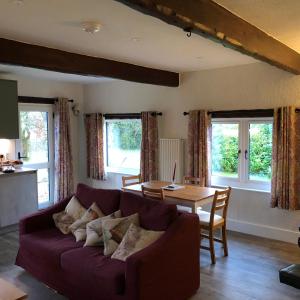 un salon avec un canapé violet et une table dans l'établissement Locka Old Hall Cottage, à Arkholme 9 autres photos