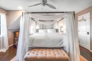 a bedroom with a white canopy bed with a ottoman at Scenic Gem: Waterfront View, Beach Access in Wading River