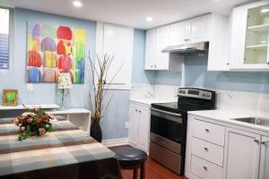 a kitchen with white cabinets and a table with flowers at Ivy Den in Oakville