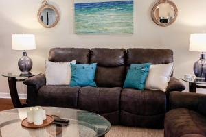 a living room with a brown couch with blue pillows at Sojourn's Sanctuary Condo Vitamin Sea Sleeps 6 in Virginia Beach