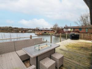 a wooden deck with a table and benches on the water at 12A Lake Escape in Carnforth