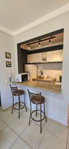 cocina con 2 sillas y encimera en Residencial Via do Café, en Ribeirão Preto