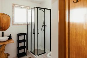 a glass shower in a bathroom with a window at Lisbon Surf Hostel in Carcavelos
