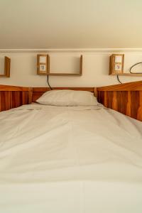 a large white bed in a bedroom with wooden walls at Lisbon Surf Hostel in Carcavelos