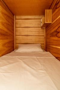 a bed in a room with a wooden wall at Lisbon Surf Hostel in Carcavelos