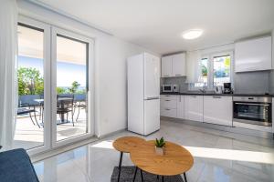 a kitchen with white cabinets and a wooden table at Apartment ILUX-1 in Novigrad Dalmatia