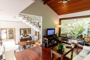 a living room with a couch and a tv and a staircase at Refúgio na Serra - Casa 3 suítes em Condomínio in Pedro do Rio