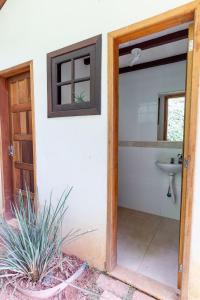 a bathroom with a sink and a door open at Refúgio na Serra - Casa 3 suítes em Condomínio in Pedro do Rio