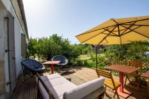 a patio with chairs and a table and an umbrella at Le grand nid in La Maurandie