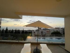 a patio with two chairs and an umbrella at Tabarja hills in ‘Ayn aş Şughayrah