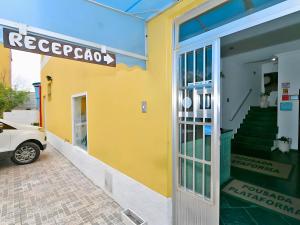 a yellow building with a car parked outside of it at Hotel Pousada Plataforma in Mongaguá