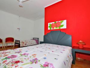 a bedroom with a bed with a red wall at Hotel Pousada Plataforma in Mongaguá