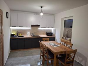 a kitchen with white cabinets and a wooden table at Domki u seseta 2 in Kluszkowce