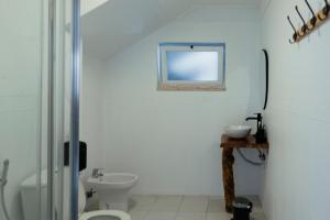 a white bathroom with a toilet and a sink at Lisbon Surf Hostel in Carcavelos