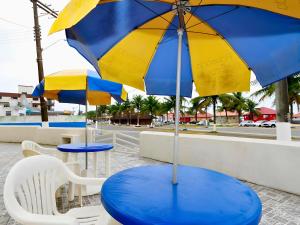 a blue and yellow table and chairs with umbrellas at Hotel Pousada Plataforma in Mongaguá