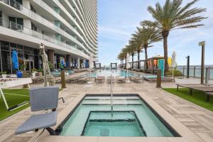 a pool at a hotel with chairs and palm trees at Corner condo, Wraparound Balcony Ocean and City Views at LYFE Resort in Hollywood