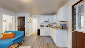 a living room with a blue couch and a kitchen at Sunny Riverside Apt Near Mit, Harvard & Red Line in Cambridge +5 photos