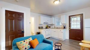 a living room with a blue couch and a kitchen at Sunny Riverside Apt Near Mit, Harvard & Red Line in Cambridge