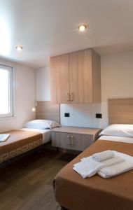 a room with two beds and wooden cabinets at Villaggio Turistico Maderno in Toscolano Maderno