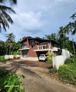 a house with a car parked in front of it at RiverMist Resort in Nilambūr